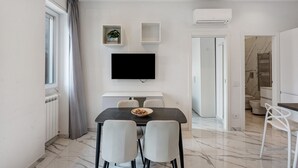 Una cocina moderna con comedor, un televisor de pantalla plana sobre la mesa y una planta pequeña en la pared.