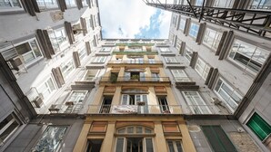 Um edifício de vários andares com varandas, janelas amplas e uma entrada central.