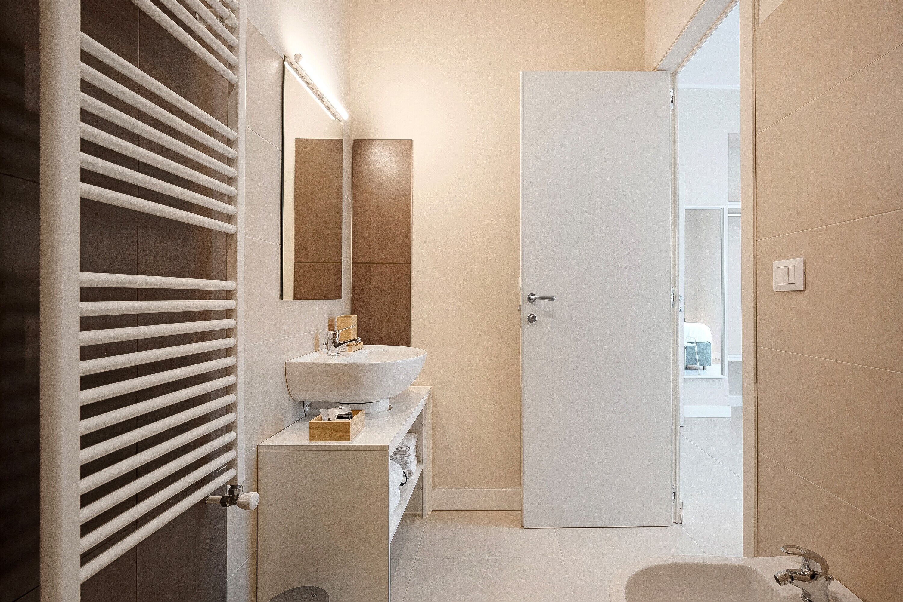 A modern bathroom with a white sink, mirror, and towel rack.