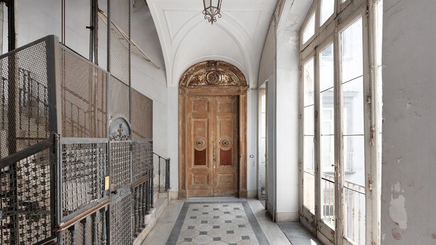A corridor with a patterned floor, a wooden door, and a metal gate. - Room 'San Severo' with Balcony, Wi-Fi and Air Conditioning (Napoli)