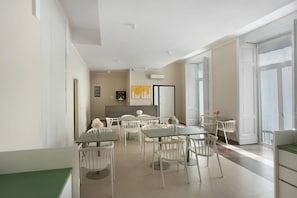 A modern dining area with white furniture, a large window, and a 'hello' sign on the wall.