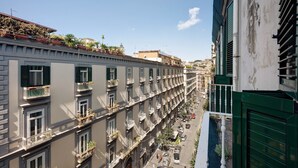 Una hilera de edificios con varios pisos y balcones, una calle al frente y un cielo despejado.