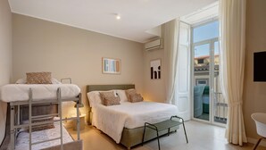 Un dormitorio con literas, una cama grande, una mesita de noche, una silla y vistas al exterior.