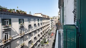 Un edificio de varios pisos con balcones, vista a la calle y cielo despejado.