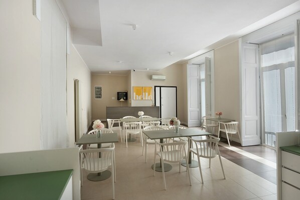 Un espace repas moderne, avec des meubles blancs, une grande fenêtre et un panneau mural sur lequel est écrit « Bonjour ».