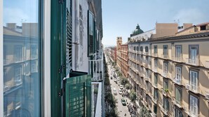 Vista de una calle con edificios, cielo despejado y una cúpula de iglesia a lo lejos.