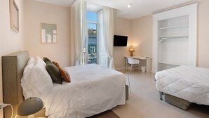 Habitación de hotel con cama, escritorio, silla, televisión y balcón.