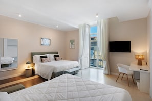 Una habitación de hotel con dos camas, un escritorio, un televisor y un balcón con cortinas.