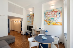 A modern living room with a fireplace, a dining area with a round table, and a hallway leading to another room.