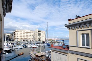 Ein Yachthafen mit vertäuten Booten, ein großes Gebäude im Hintergrund und ein klarer Himmel.