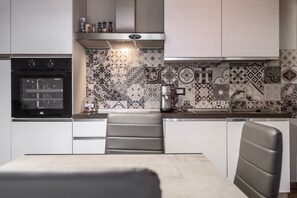 Une cuisine moderne dotée d’un four encastré, d’une machine à café et d’un crédence décorée.