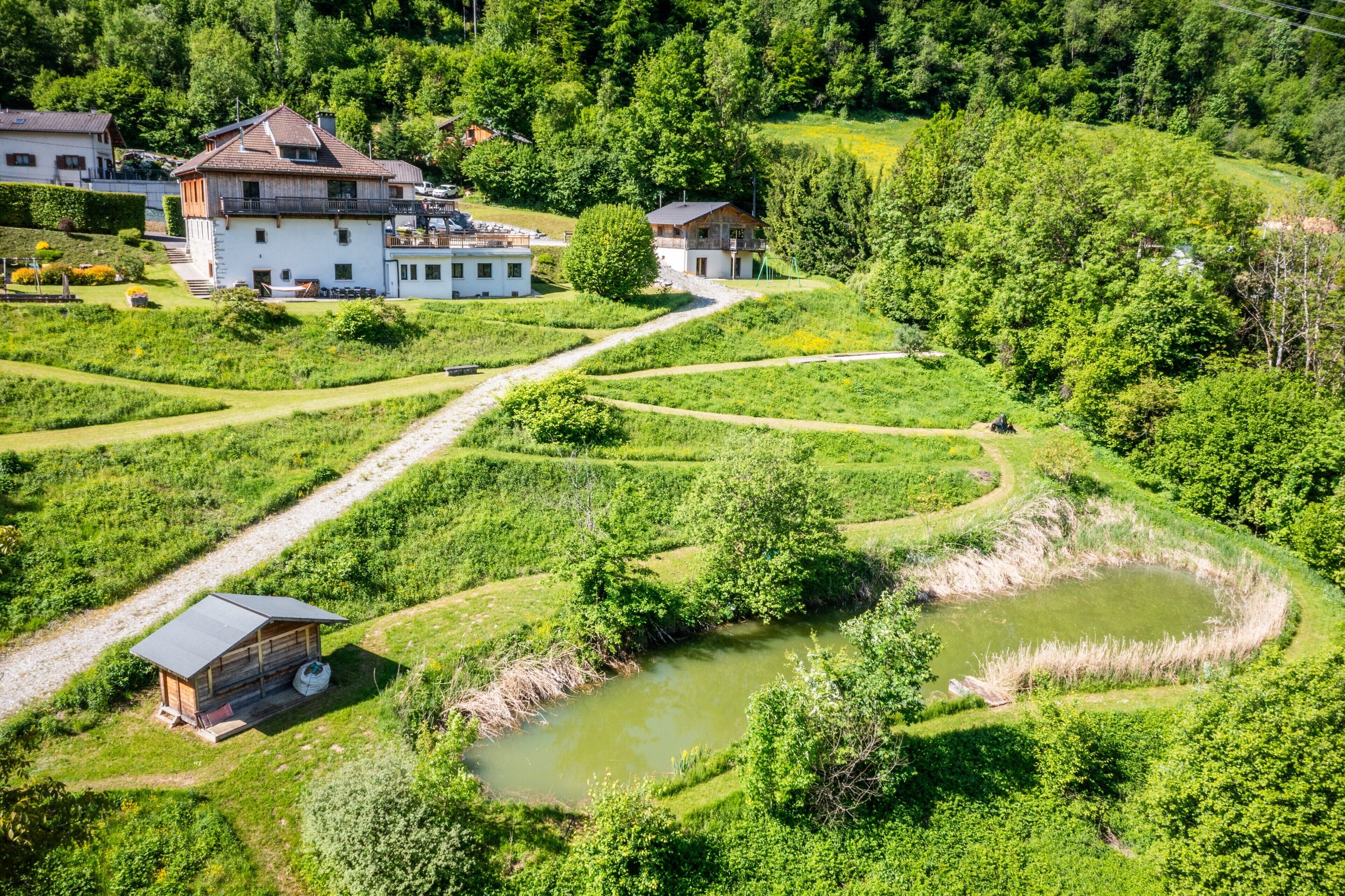 Paesaggio rurale con campi a terrazze, uno stagno e due case con balconi.