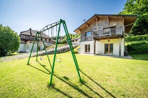 Ein Wohngebiet mit Schaukel, einem Haus mit Balkon und einem gepflegten Rasen.
