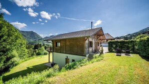 Een huis met een schuin dak, een klein terras en een verzorgd gazon.