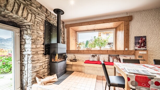 A stone wall, a fireplace, a wooden bench, a table with chairs, and a window with a view. - Cottage 'Leyetaz' with Lake View, Private Terrace and Wi-Fi (Châtillon-sur-Cluses)