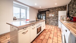 A kitchen with a stone wall, wooden countertop, and a window overlooking a snowy landscape. - Cottage 'Leyetaz' with Lake View, Private Terrace and Wi-Fi (Châtillon-sur-Cluses)