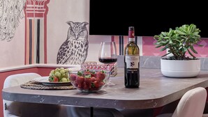 A dining table with a bowl of strawberries, a wine bottle, and a potted plant. - Apartment 'Royal Suite' with Wi-Fi and Air Conditioning (Firenze)
