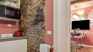 A kitchen with a stone wall, a Bosch microwave, a red kettle, and a THES brand kettle on the counter. - Apartment 'Royal Suite' with Wi-Fi and Air Conditioning (Firenze)