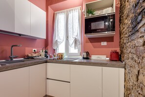 A kitchen with white cabinets, a Bosch microwave, a kettle, and a red toaster.