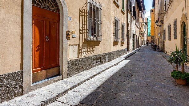 A narrow cobblestone street flanked by buildings with arched doorways and barred windows. - Apartment 'Royal Suite' with Wi-Fi and Air Conditioning (Firenze)