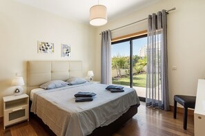 A bedroom with a bed, bedside tables, a lamp, a chair, and a view of the outdoors. - Holiday Home 'Peva' with Private Pool, Wi-Fi and Air Conditioning (Albufeira)