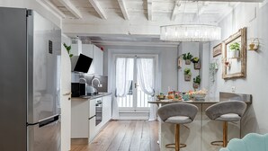 Une cuisine moderne avec un réfrigérateur en acier inoxydable, un ordinateur portable posé sur le comptoir et un coin repas équipé de deux tabourets de bar.