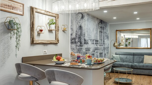 Une cuisine moderne avec un îlot central, des tabourets de bar, un lustre et une fresque murale.