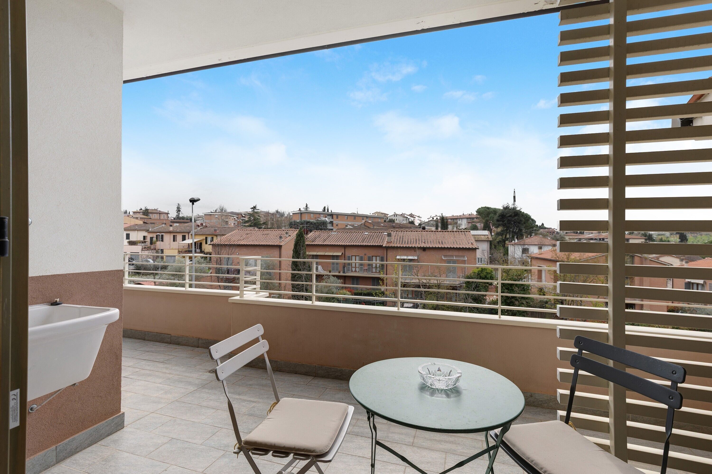 Un balcon avec une table, des chaises et une vue sur un quartier résidentiel.