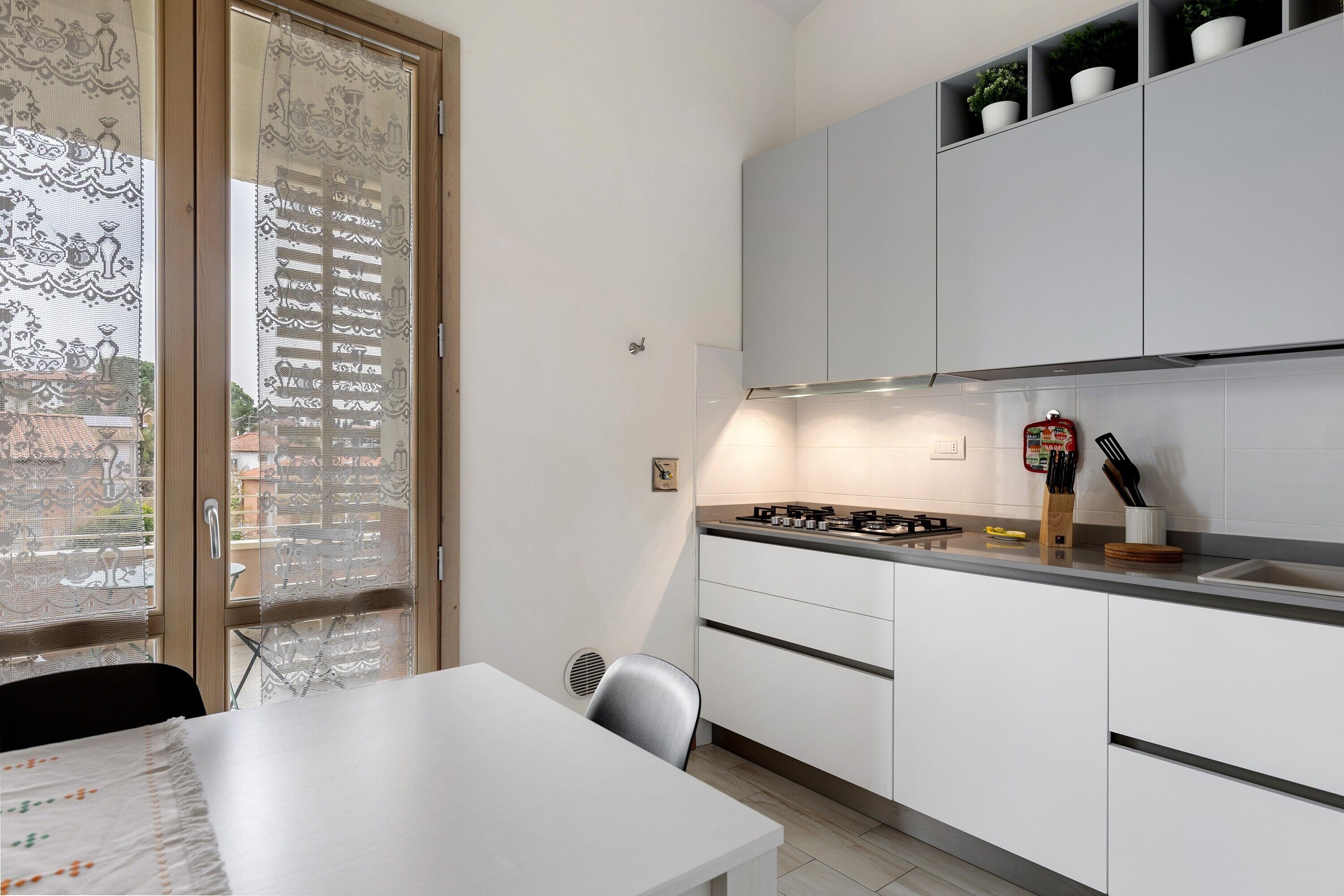 Une cuisine moderne avec des meubles blancs, une cuisinière à gaz et un coin repas comprenant une table et des chaises.
