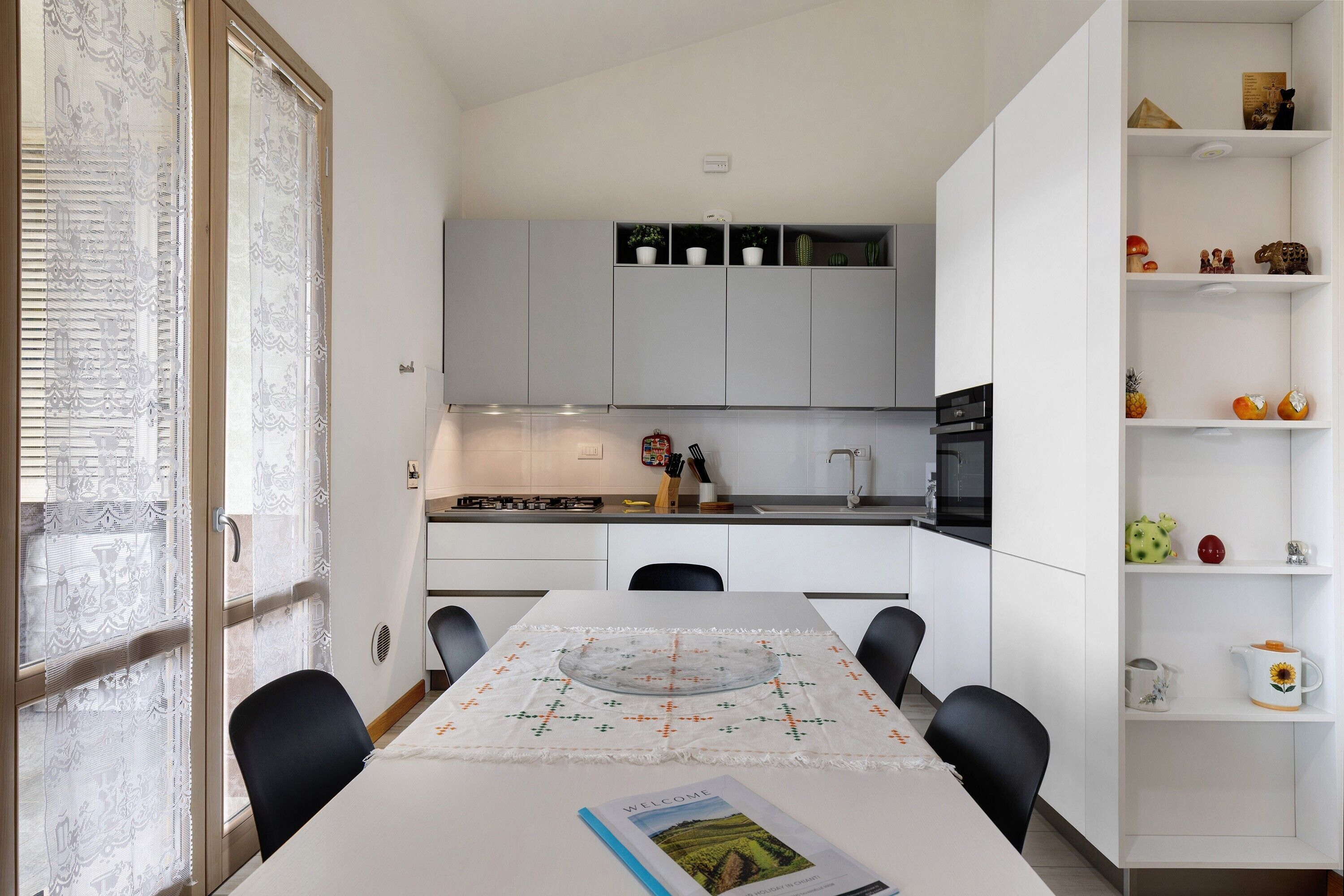 A modern kitchen with white cabinets, a dining table with chairs, and a decorative glass top.