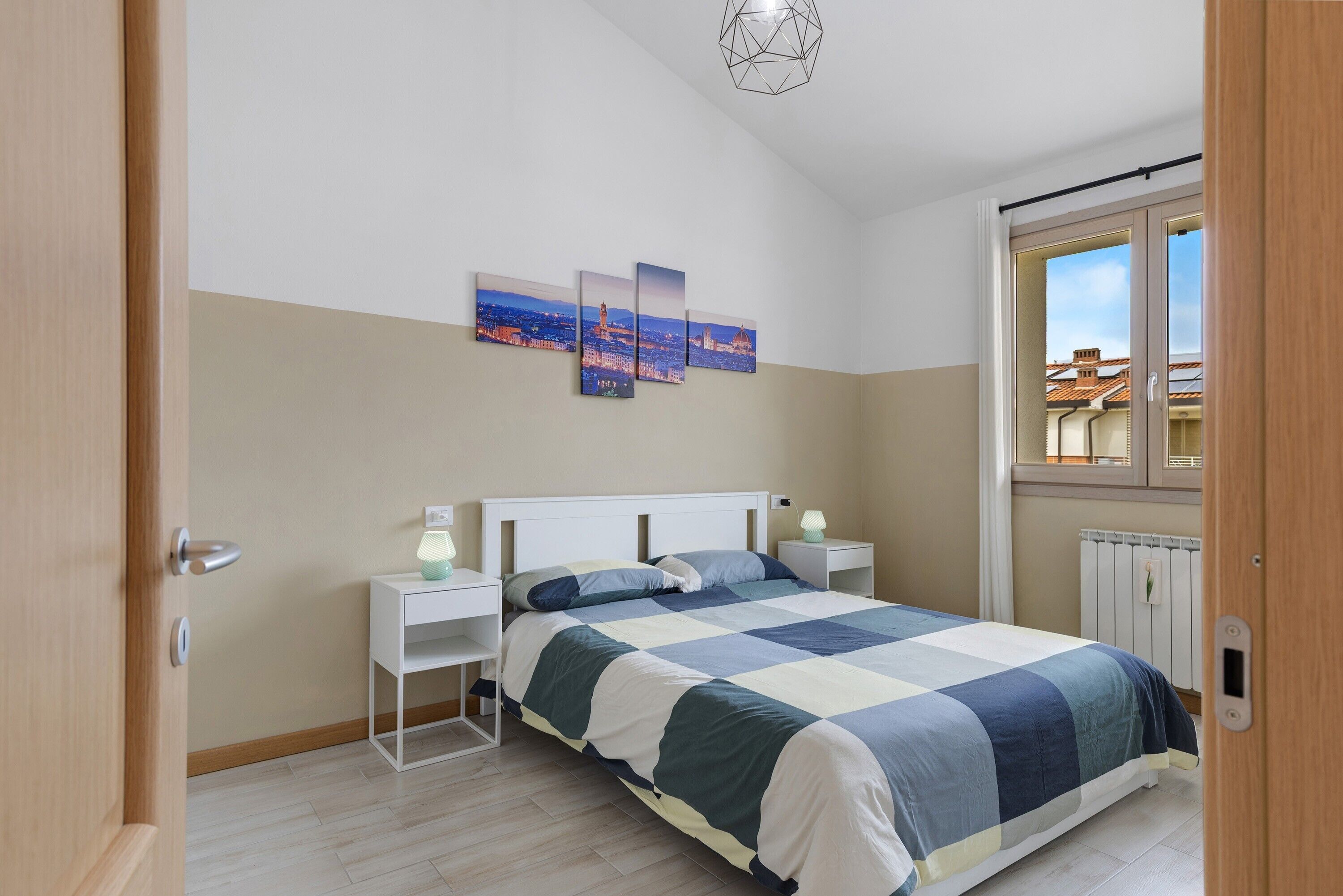 A bedroom with a bed, bedside tables, a window, and a radiator.