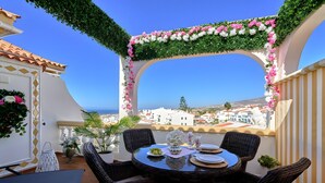 An outdoor patio with a round table, wicker chairs, and a view of the city.