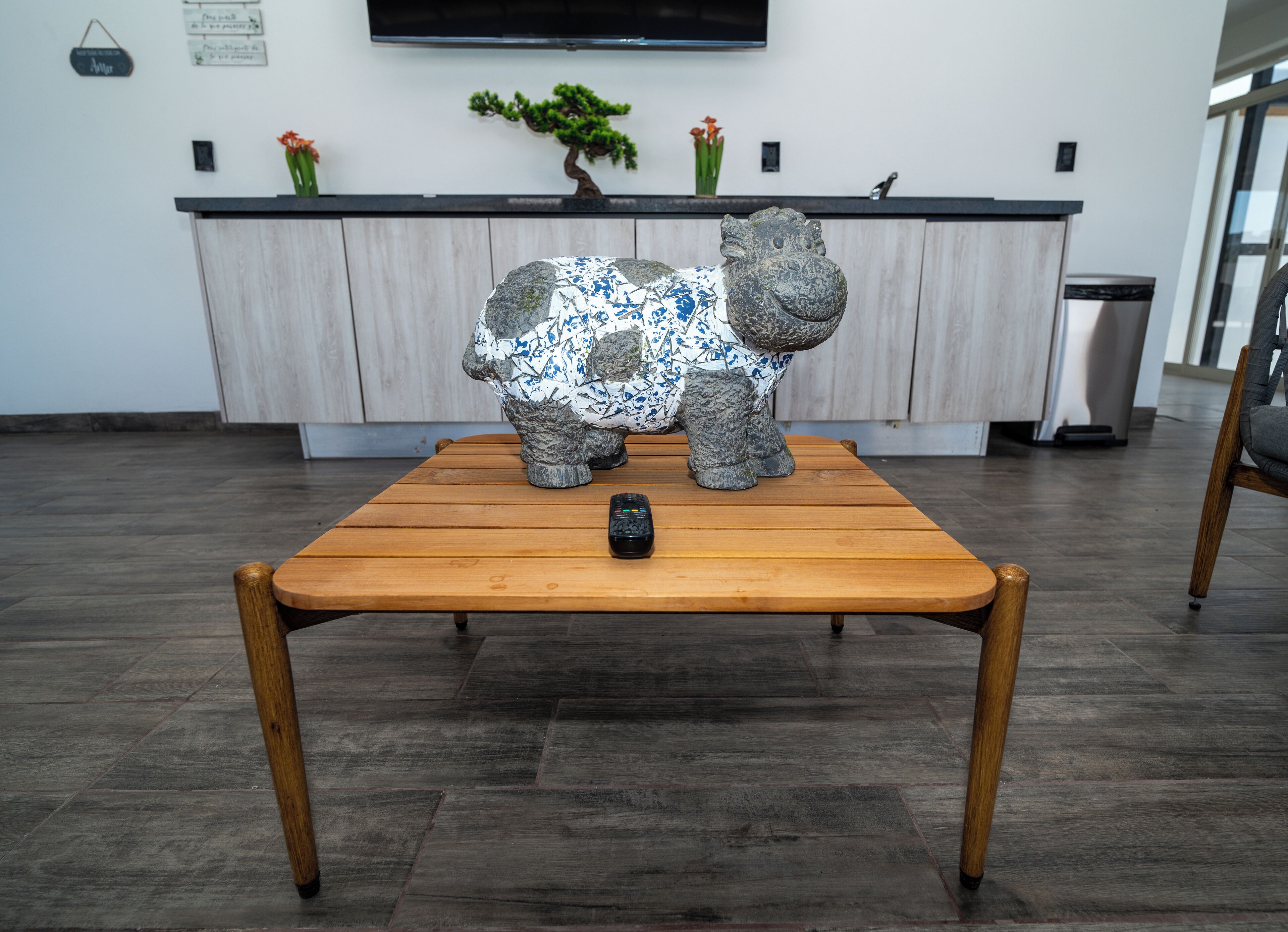 A wooden table with a remote control and a decorative elephant sculpture.