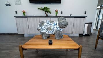 A wooden table with a remote control and a decorative elephant sculpture.