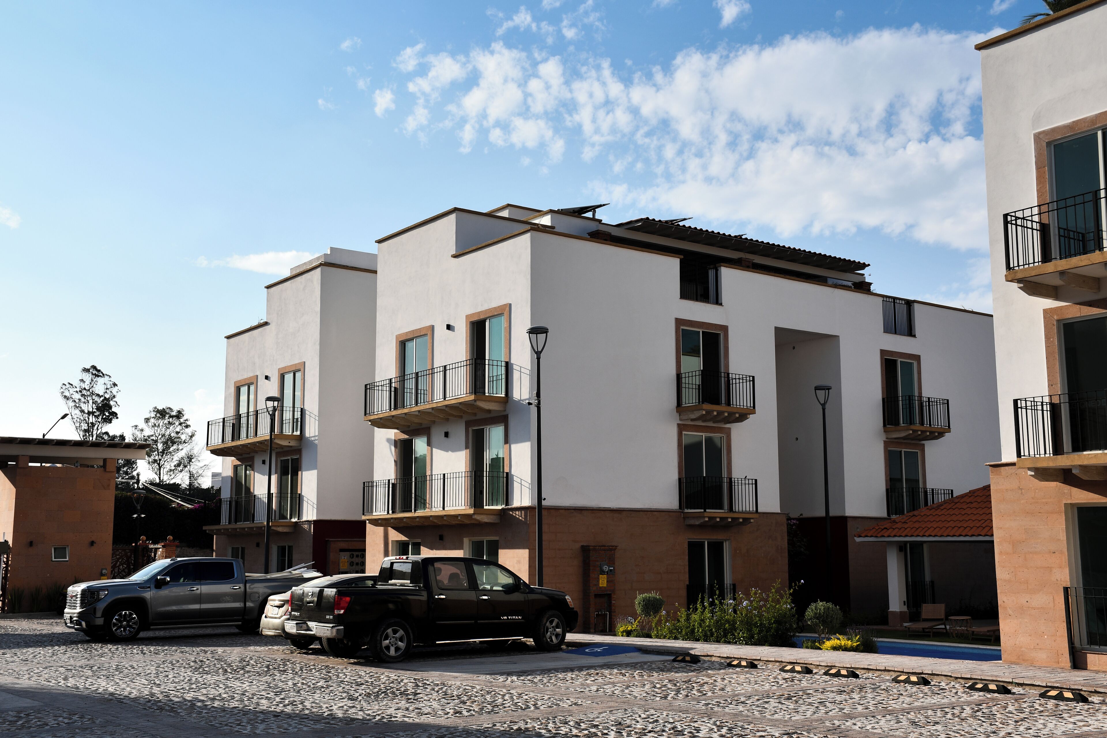 A modern apartment building with multiple balconies, a parking area, and a small pool.