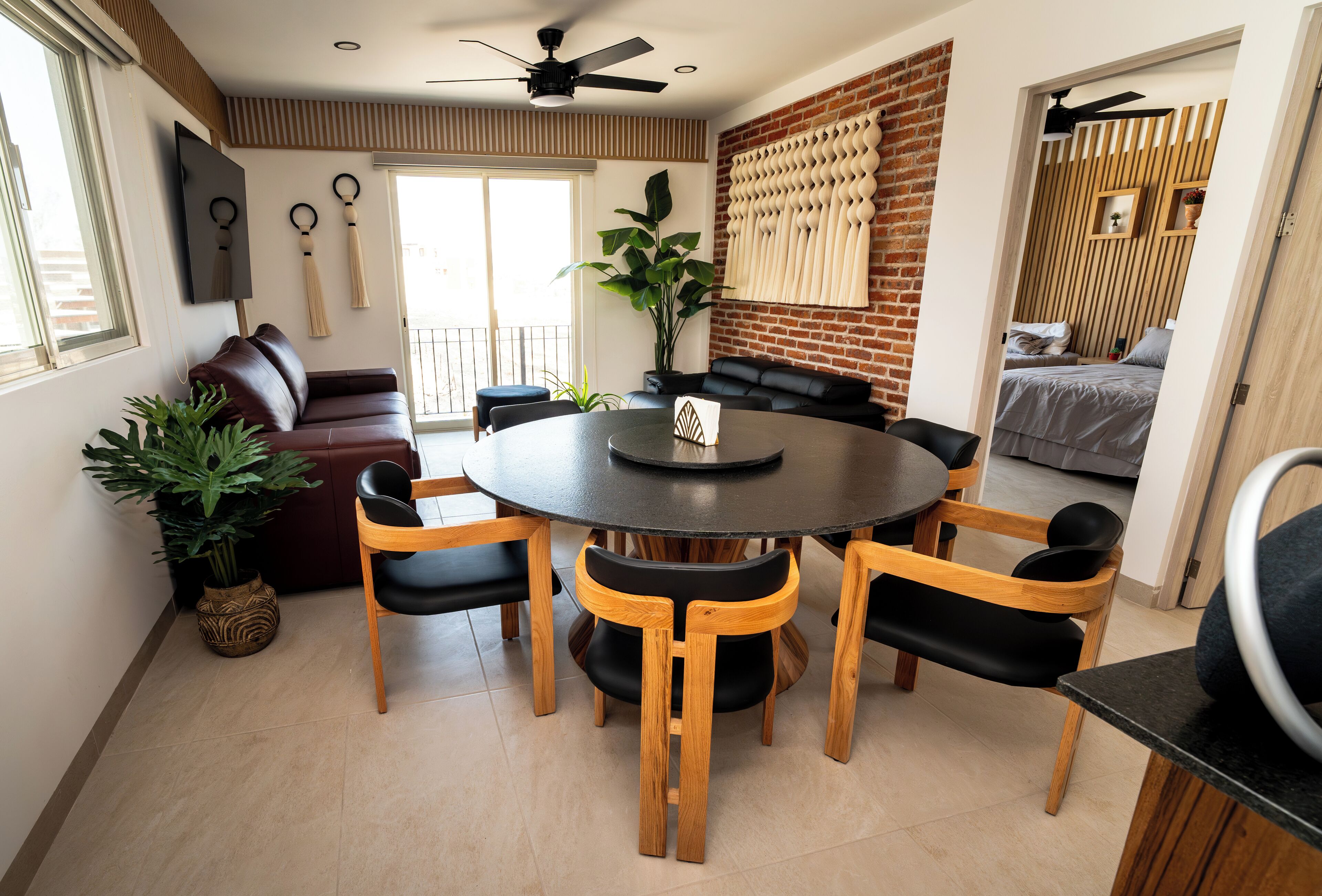 Un comedor moderno con una mesa redonda, sillas de madera y un ventilador de techo.