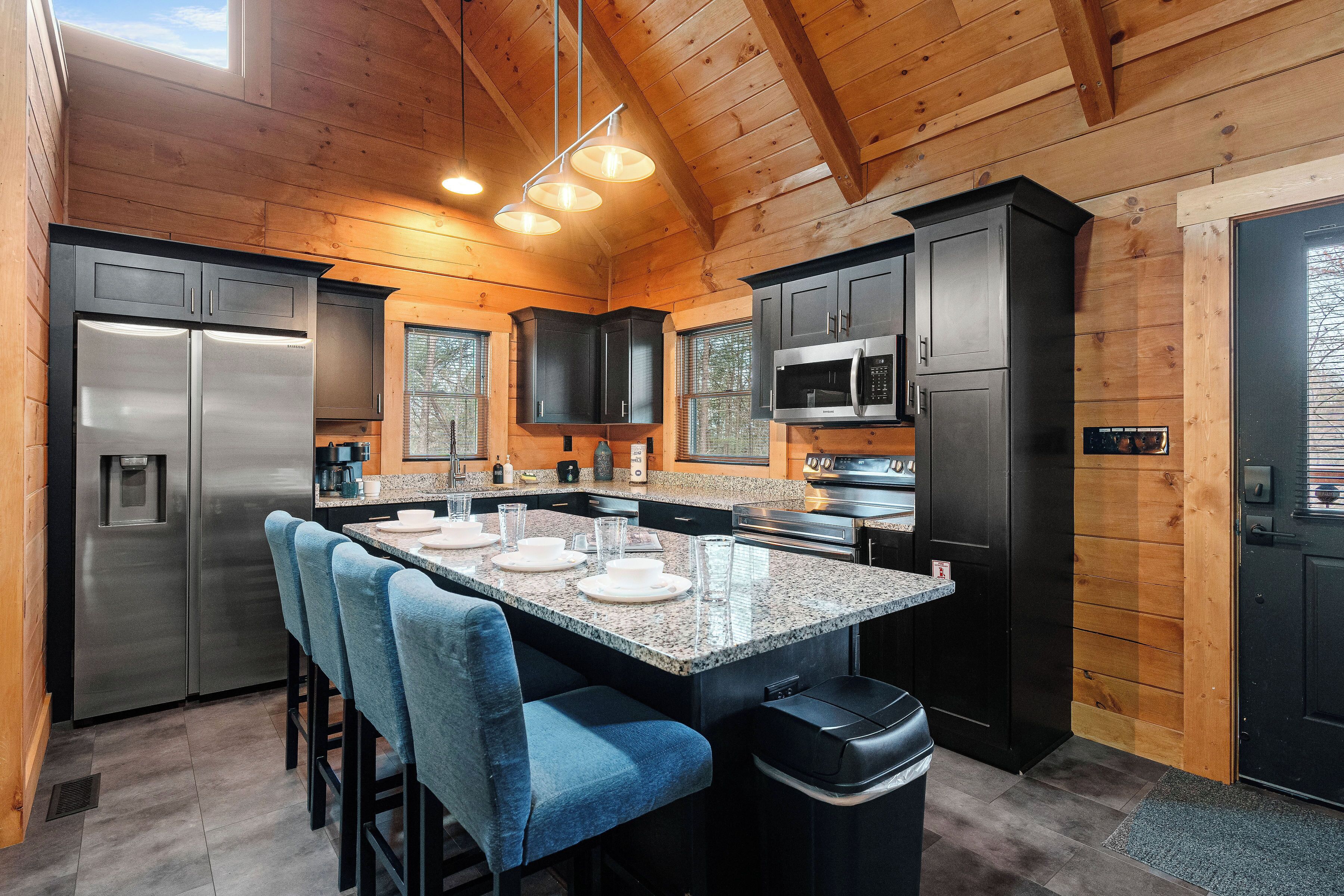 A modern kitchen with granite countertops, stainless steel appliances, and bar seating.