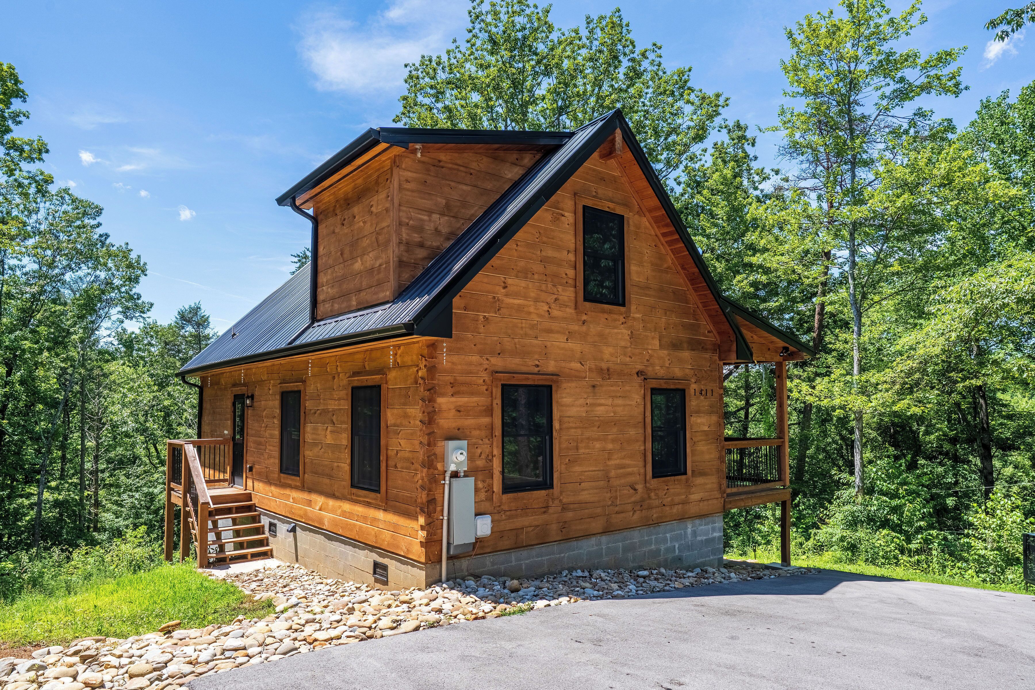 A wooden cabin with a sloped roof, a front porch, and a stone foundation.
