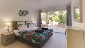 A bedroom with a bed, nightstands, a dresser, and a large window with curtains. - Padulaccia by Pinarello Villa Services (Sainte-Lucie de Porto-Vecchio)