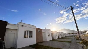 Une rangée de maisons modernes à un étage, avec un ciel dégagé et une montagne en arrière-plan.