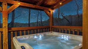 A wooden deck with a hot tub, surrounded by trees and a night sky view. - Charming Cabin in the Smokies -close to attractions, Hot Tub, Pool Table, Arcade (Sevierville)