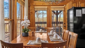 A wooden dining room with a table set for four, large windows, and a black refrigerator. - Charming Cabin in the Smokies -close to attractions, Hot Tub, Pool Table, Arcade (Sevierville)