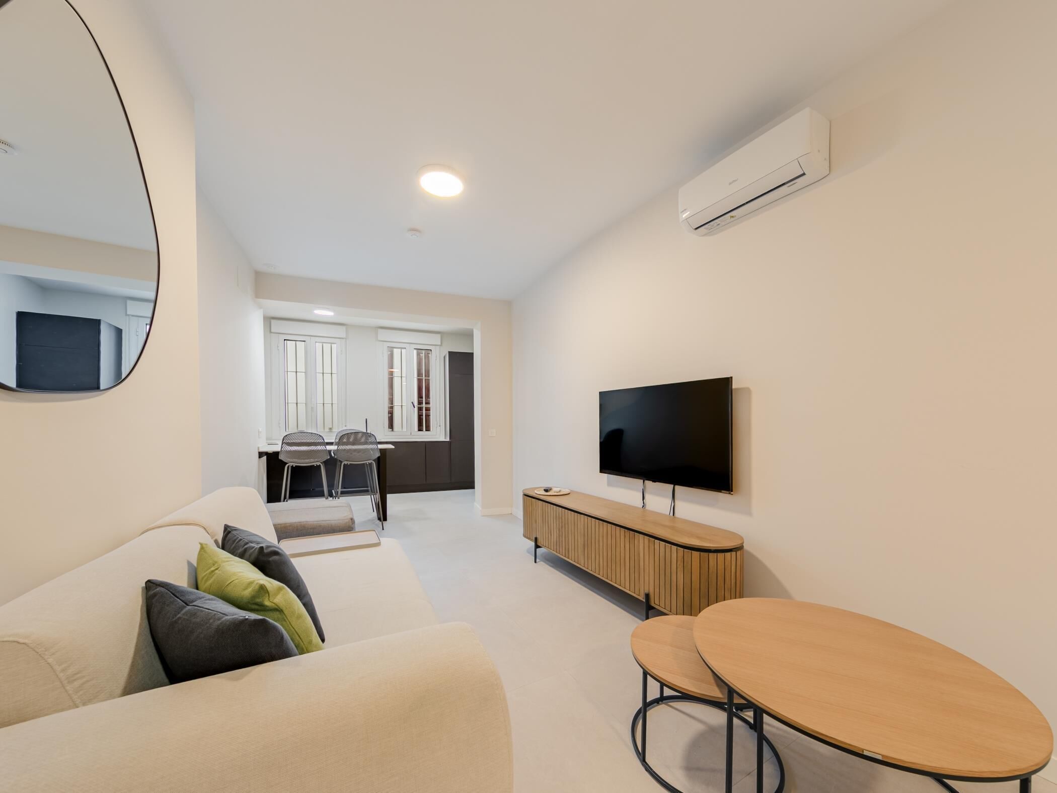 Ein modernes Wohnzimmer mit einer Couch, einem Couchtisch, einem Fernseher und einem Essbereich mit Stühlen und einem Tisch.