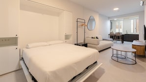 A modern hotel room with a large bed, a desk, and a seating area. - Alameda estudio deluxe (Sevilla)