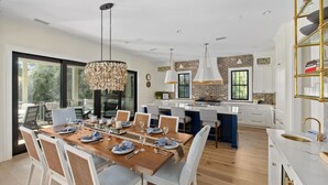 A modern kitchen with a central island, white cabinetry, and a hanging light fixture.