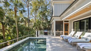 A poolside area with lounge chairs, a pool, and a building with large windows.