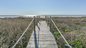 A wooden boardwalk leading to a beach with a clear sky.