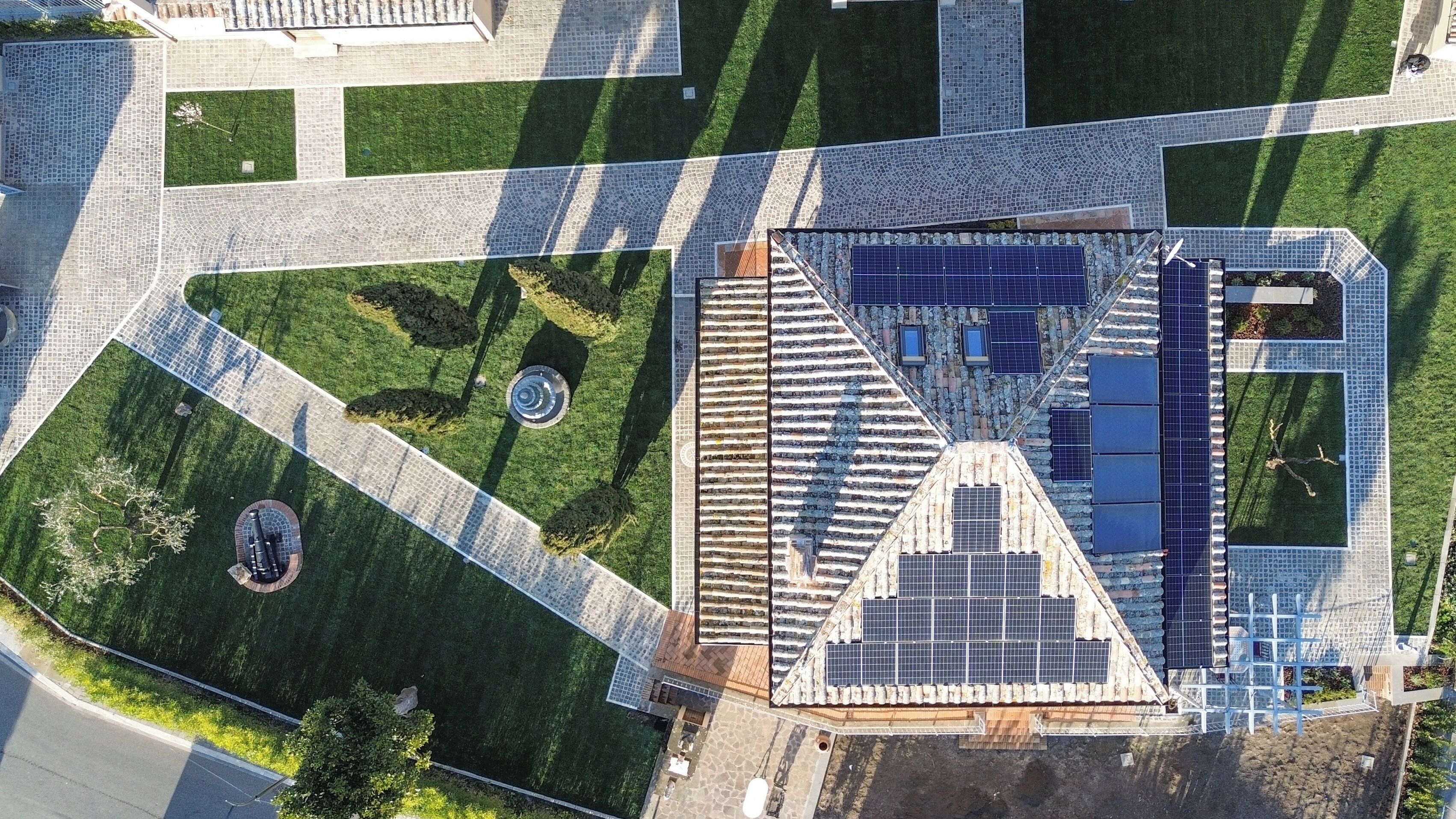 Eine Luftaufnahme eines Gebäudes mit einer markanten, dreieckigen Dachkonstruktion, Solaranlagen und einem zentralen, kreisförmigen Innenhof.