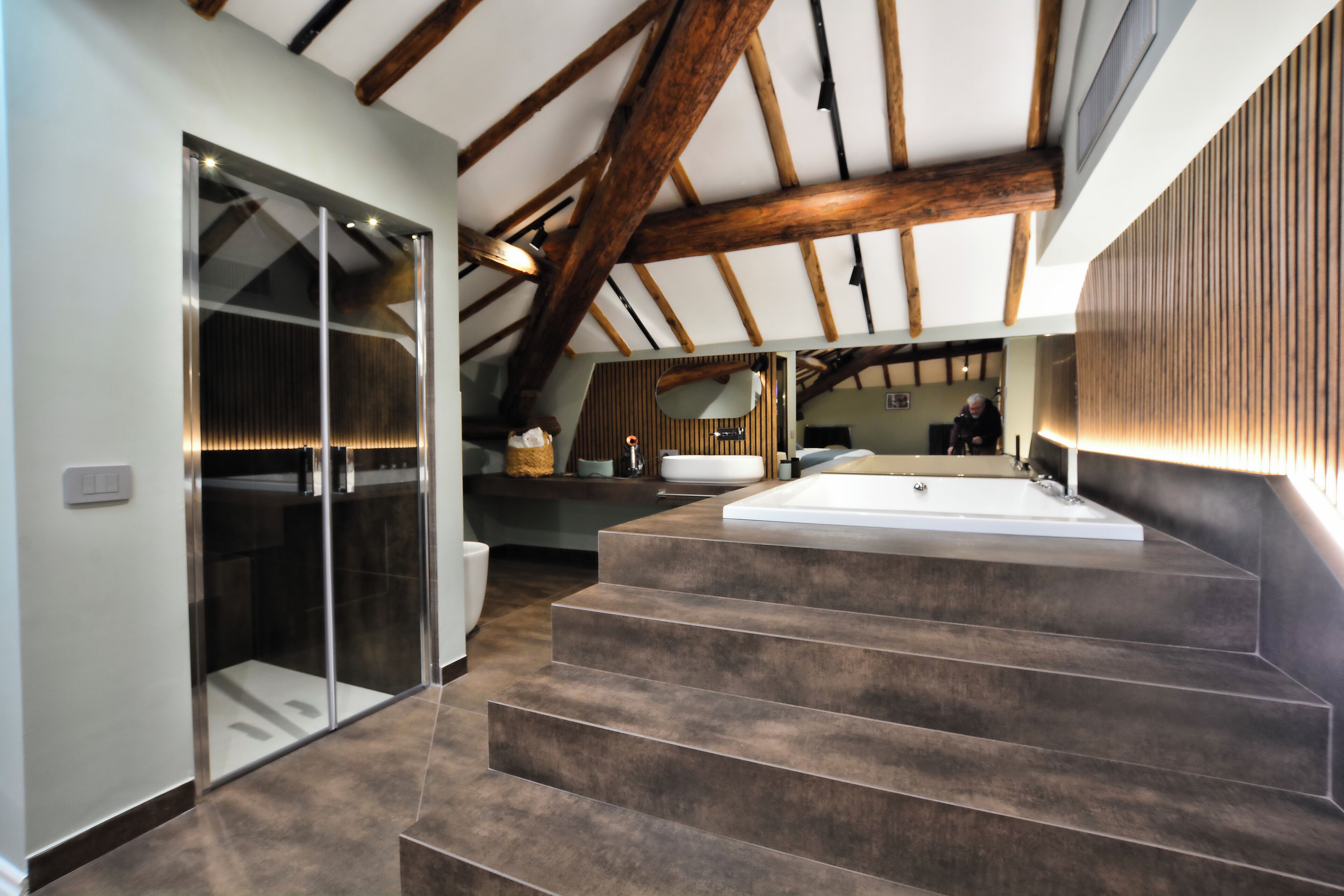Un baño moderno con una bañera independiente, cabina de ducha con paredes de vidrio y techo de madera.