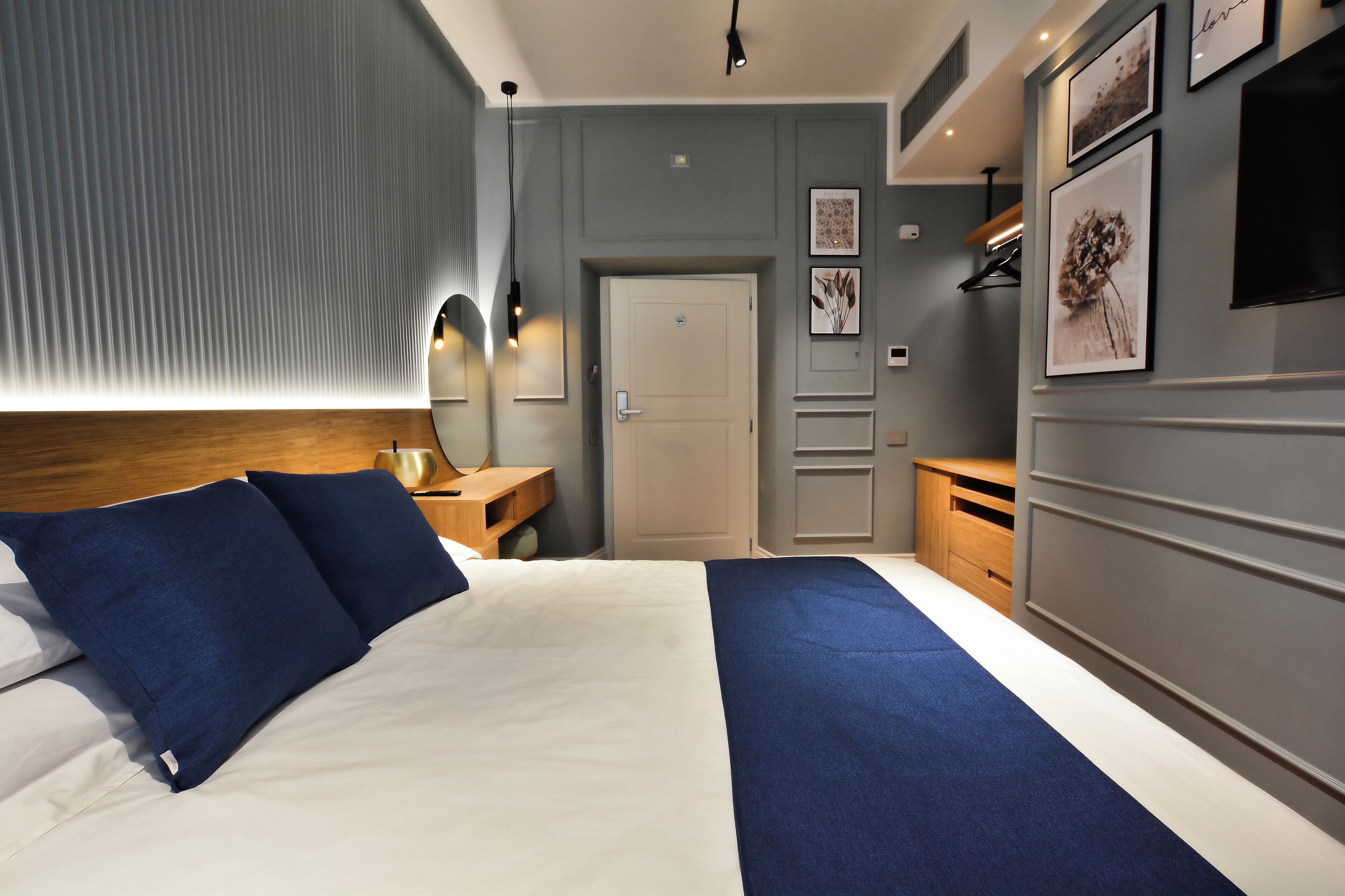Un dormitorio moderno con una cama grande, mesitas de noche, un armario y una puerta.